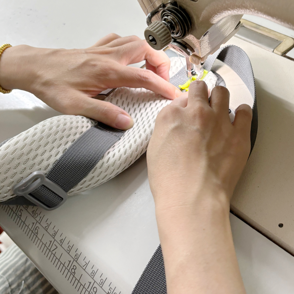 A worker sewing shoulder strap for baby carriers mass production by using a sewing machine