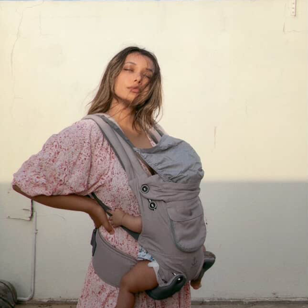 A mom wearing a baby in a infant carrier and enjoying sunshine