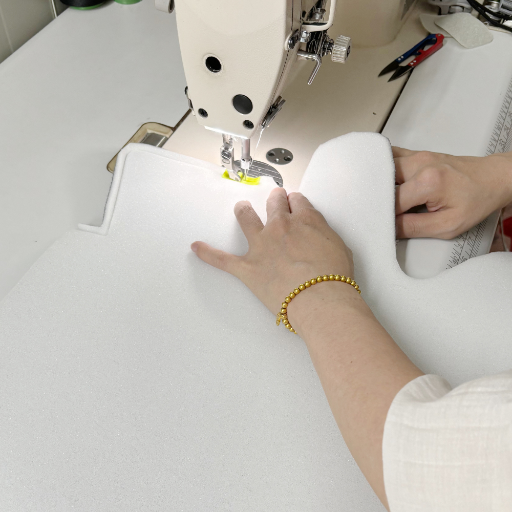 Person using a sewing machine on a white sponge
