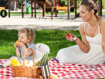 Mother and child picnic on lawn with kid sitting in inflatable outdoor seat