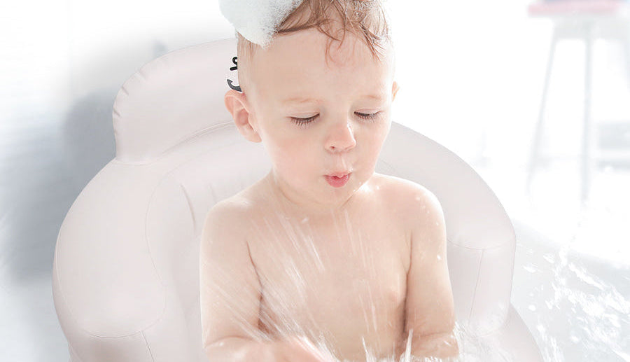 A happy baby enjoying bubble bath time, comfortably sitting in a LUFFCABO inflatable bath seat