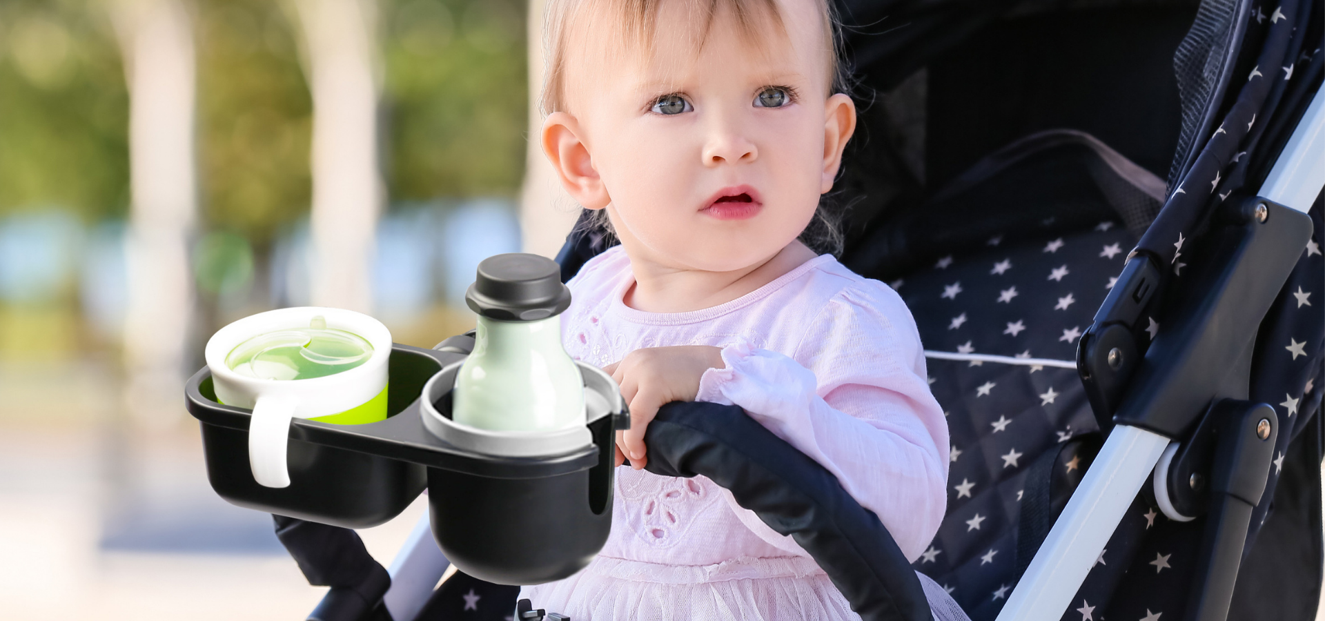 Child in stroller with snack tray and cup holder containing bottle and cupslider_item_kWqTkj