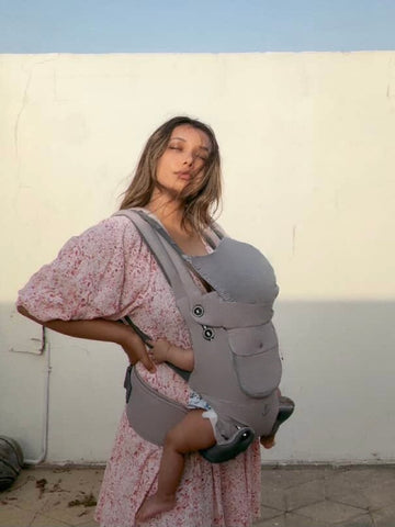 A mom holding a baby in a infant carrier 