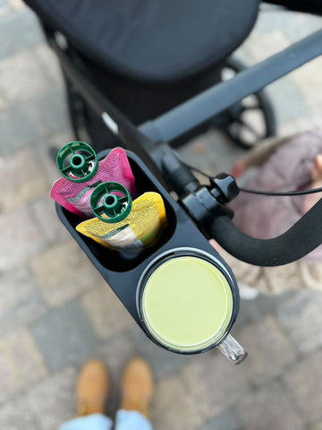 Stroller tray with baby essentials attached to a stroller handle